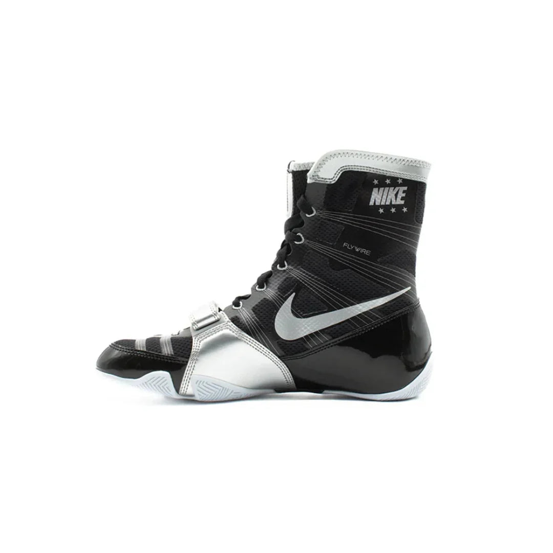 A Nike boxing boot in black and silver, featuring the Nike Swoosh and 'NIKE BOXING' branding on the ankle collar, shown against a plain white background.
