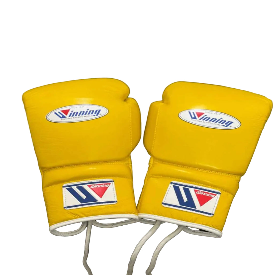 Pair of yellow boxing gloves with a brand logo on a black stool.