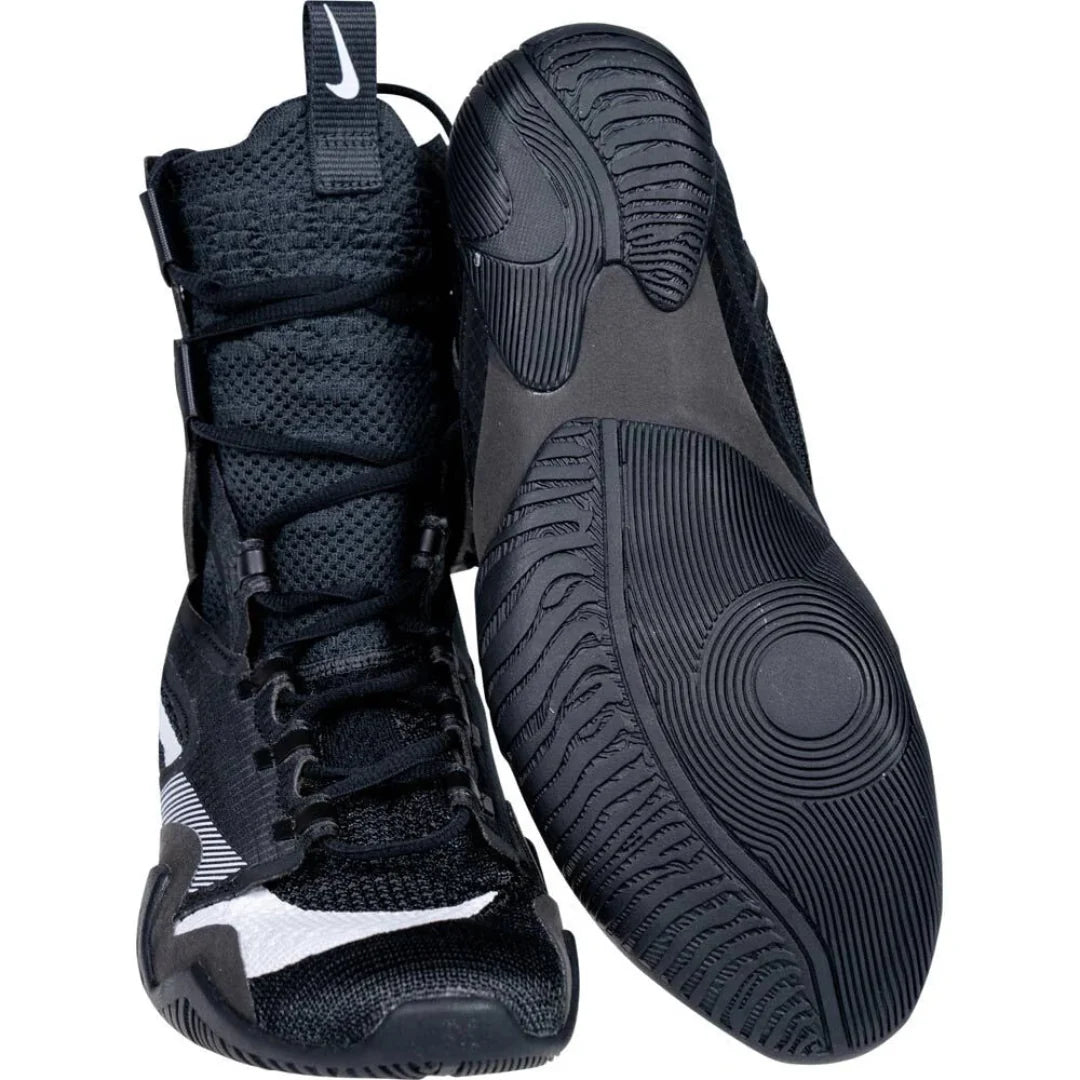 A pair of black high-top athletic sneakers shown on a white background, with one shoe standing upright and the other lying on its side to display the textured black outsole.